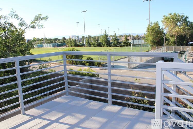 A white railing overlooks a green field.