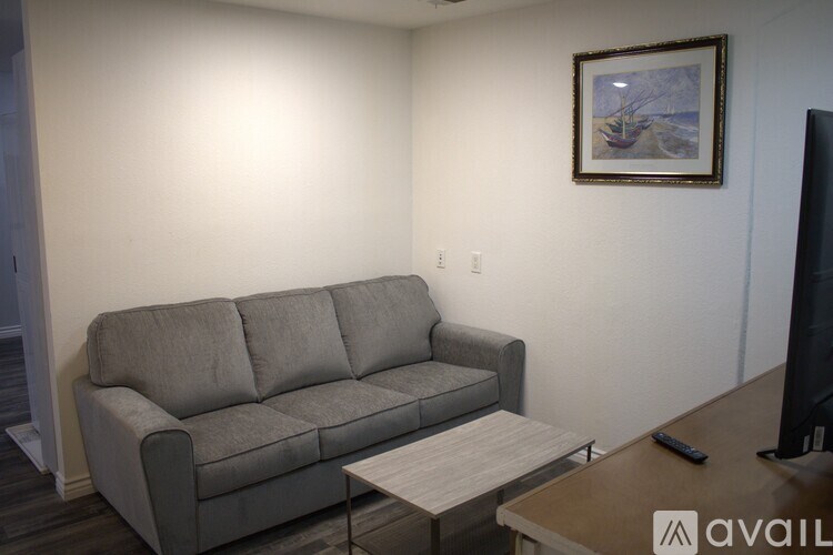 A grey couch with a coffee table in front of it and a painting on the wall.
