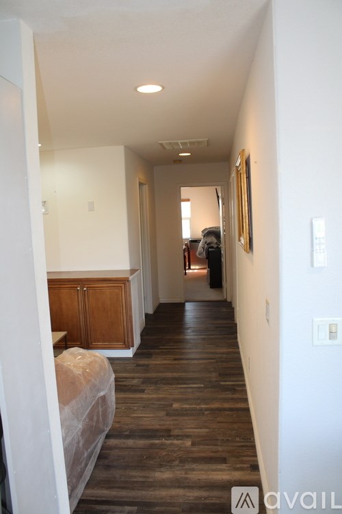 A hallway with wood floors and white walls.