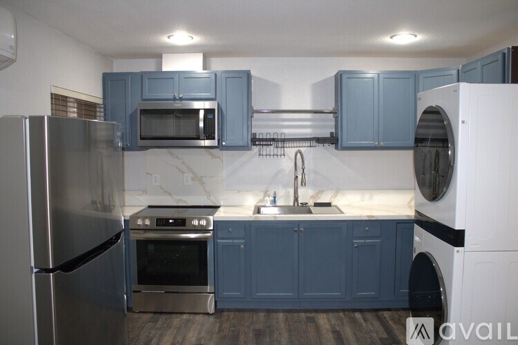 A kitchen with a refrigerator, oven, microwave, and washing machine.