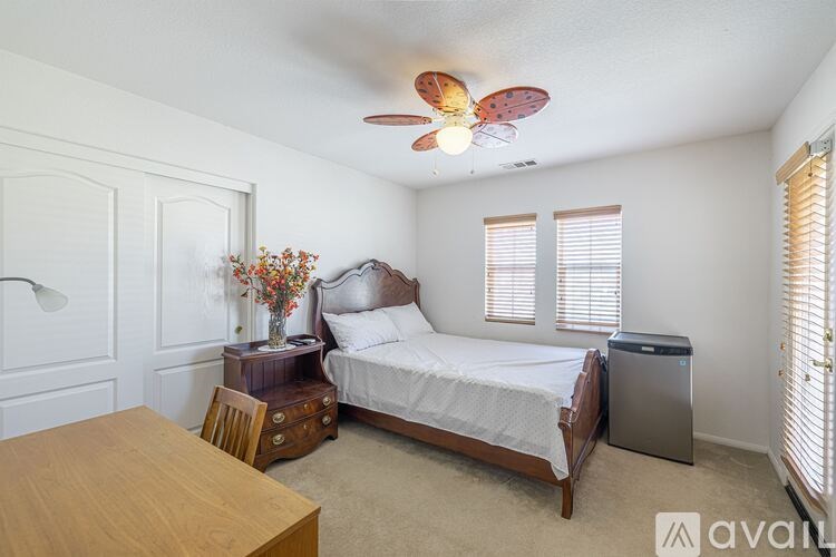 A bedroom with a bed, dresser, and ceiling fan.