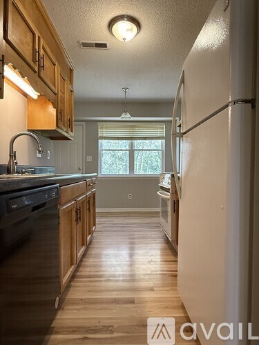 A kitchen with wooden cabinets and a black dishwasher.