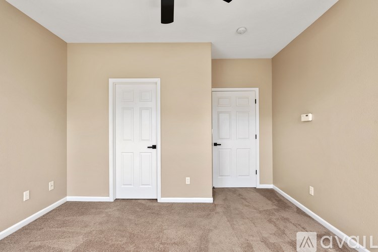 A room with two white doors and carpeted flooring.