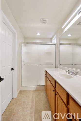 A bathroom with a sink, mirror, and shower.