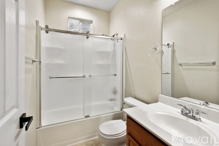 A white bathroom with a toilet, sink, and shower.