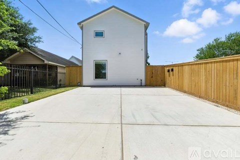 A white house with a black fence and a wooden wall on the right side.