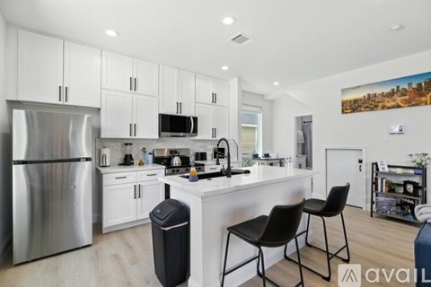 A kitchen with white cabinets and a stainless steel refrigerator.