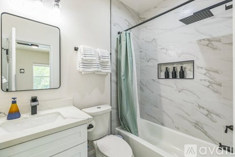 A white bathroom with a marble wall and a white toilet.