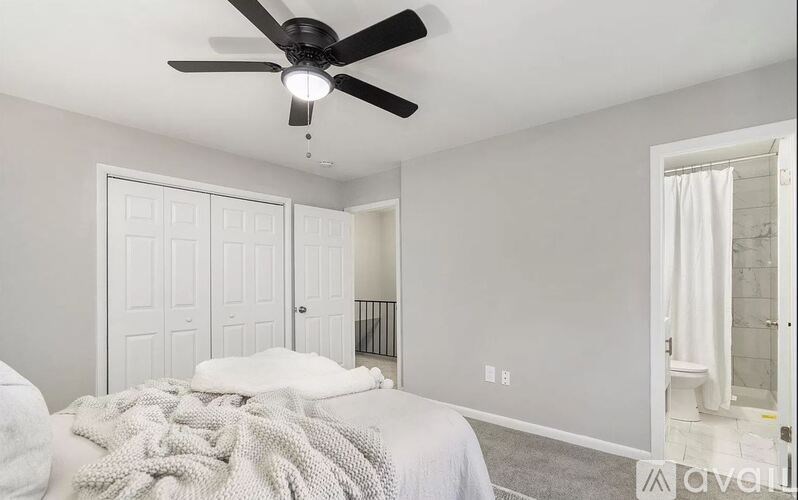 A bedroom with a bed, a ceiling fan, and a window with a curtain.