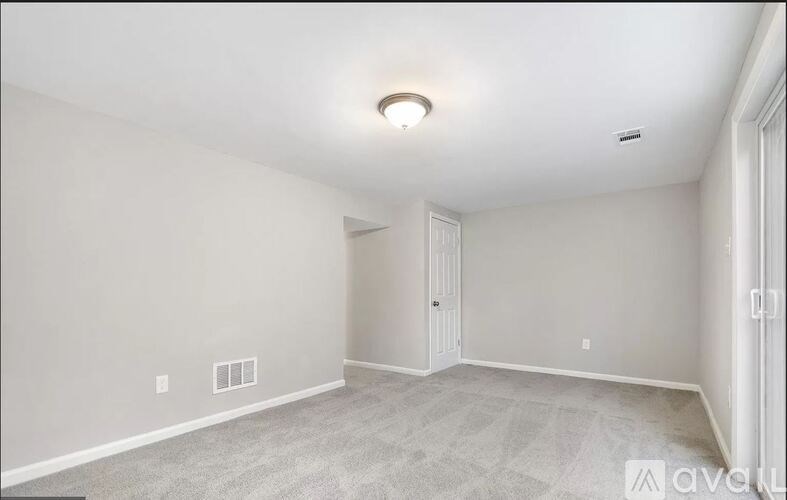 A spacious room with a carpeted floor and a ceiling light.