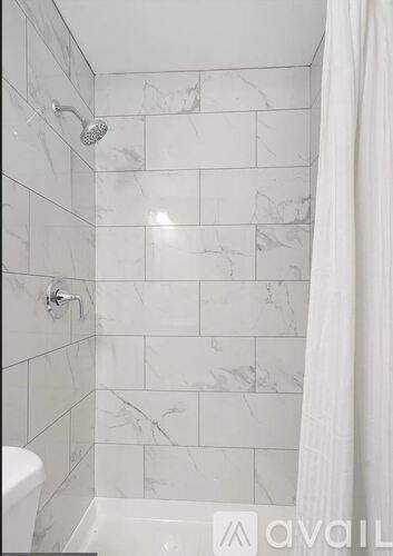 A white bathroom with a marble tile shower.