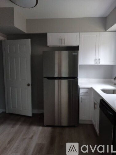 A kitchen with a stainless steel refrigerator and white cabinets.