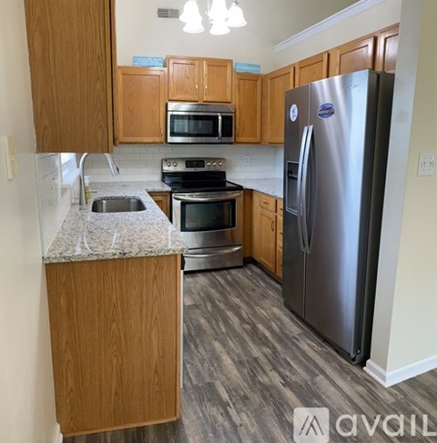A kitchen with wooden cabinets and a stainless steel refrigerator.