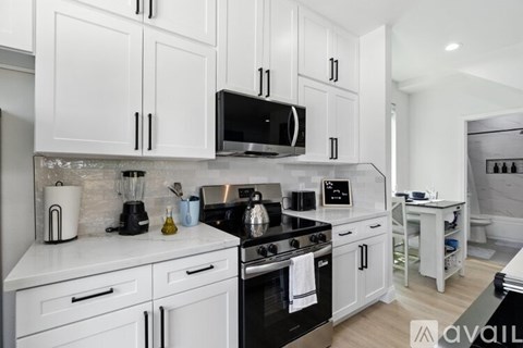 A modern kitchen with white cabinets and black appliances.