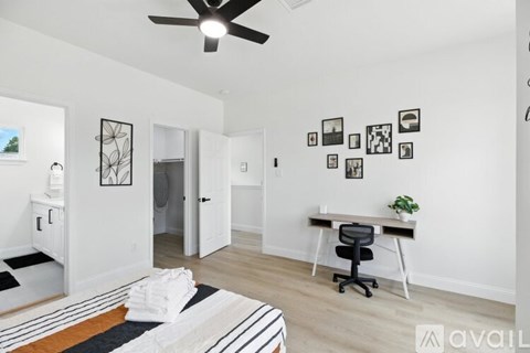 A room with a ceiling fan and a desk with a chair.