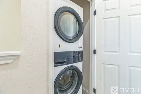 A washing machine is installed in a small space between a wall and a door.