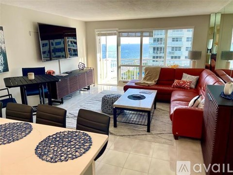 A living room with a red couch and a dining table with chairs.