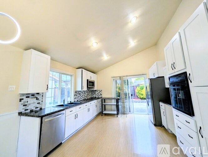 A kitchen with white cabinets and a black countertop.