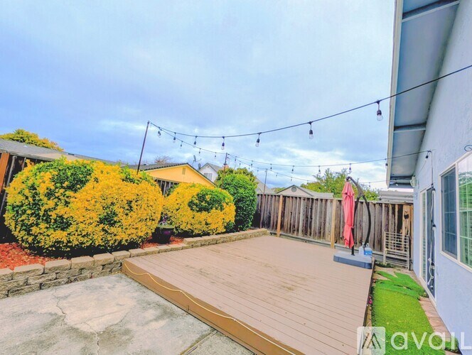 A backyard with a wooden deck and a wall with a window.