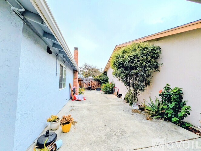 A patio area with a table, chairs, and potted plants.