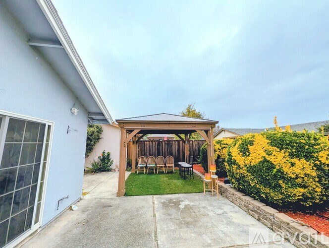 A backyard with a wooden pergola and a table set up under it.