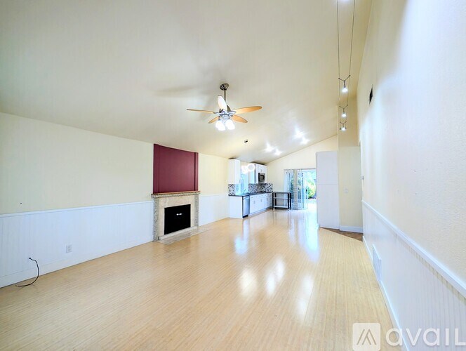 A spacious room with a fireplace and a ceiling fan.