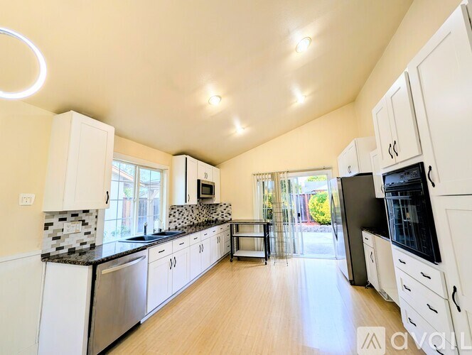 A kitchen with white cabinets and a black countertop.