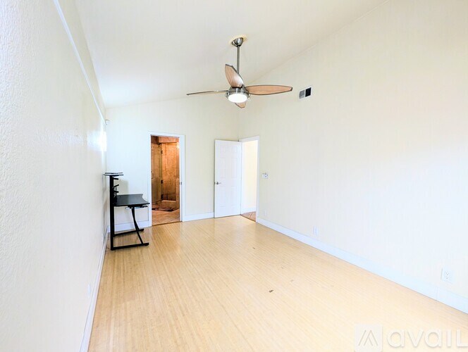 A room with a ceiling fan and a wooden floor.