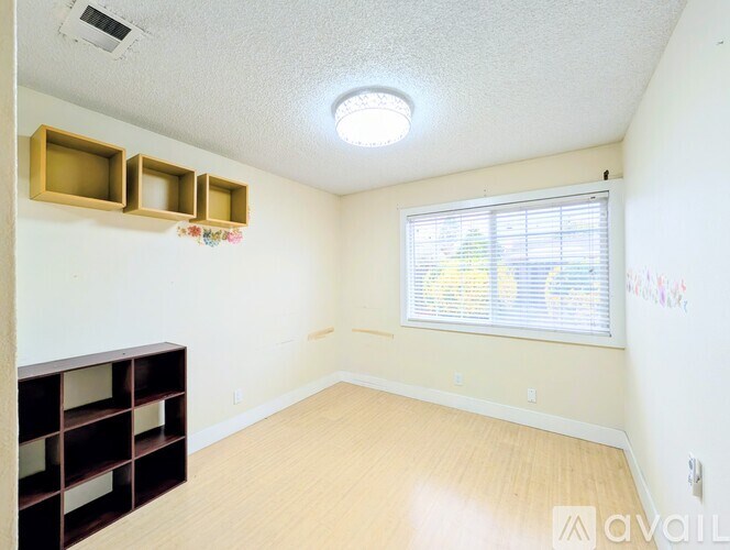 A room with a window, wooden shelves, and a ceiling light.