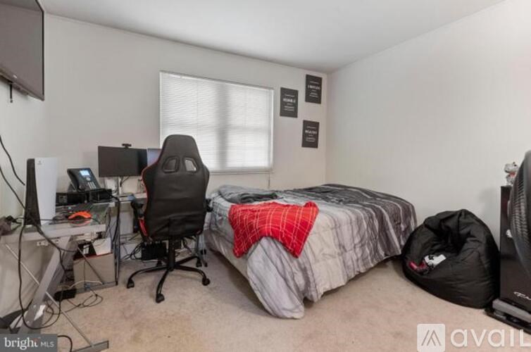 A bedroom with a bed, desk, and computer setup.