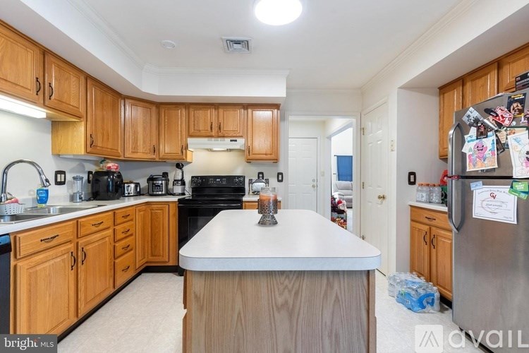 A kitchen with wooden cabinets and a white island.
