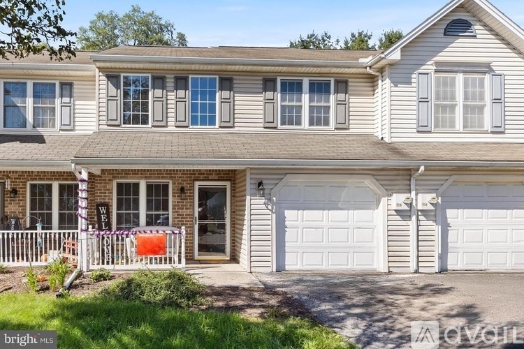 A two-story house with a white garage door and a brown roof.