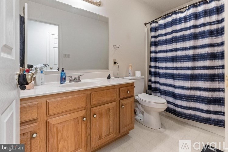 A bathroom with a wooden vanity and a blue and white striped shower curtain.