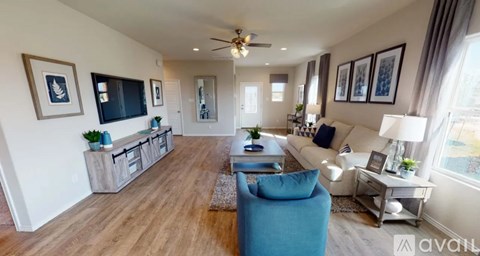 A living room with a blue chair and a television on the wall.