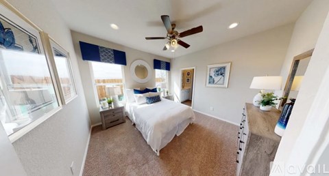A bedroom with a bed, a ceiling fan, and a window with a view of a building outside.