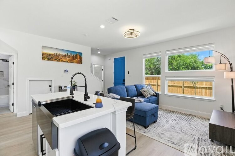 A modern kitchen with a sink, stove, and blue sofa.