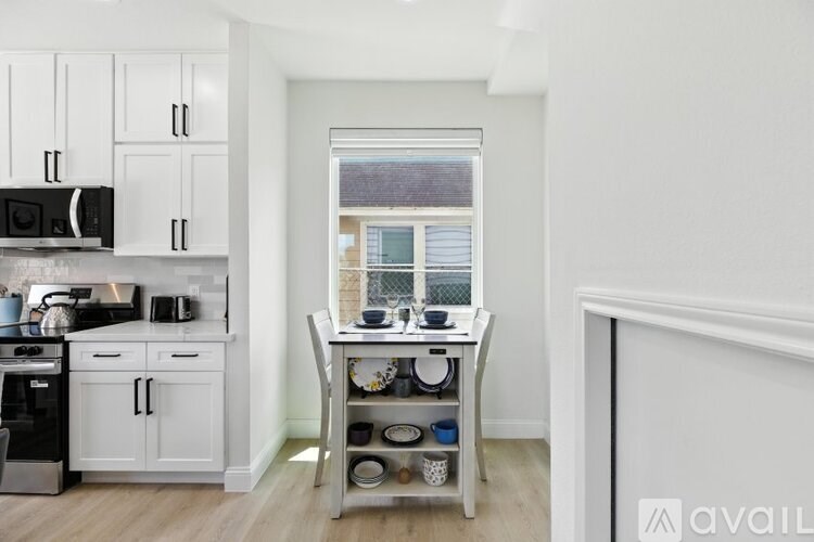 A kitchen with white cabinets and a black microwave.