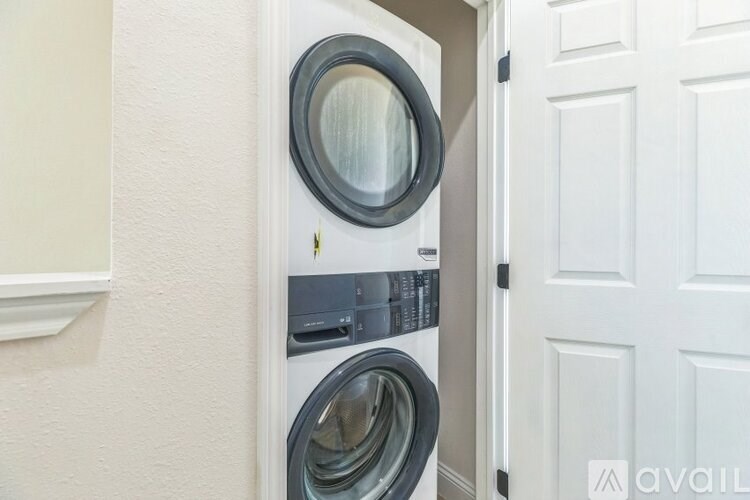 A washing machine is installed in a small space between a wall and a door.