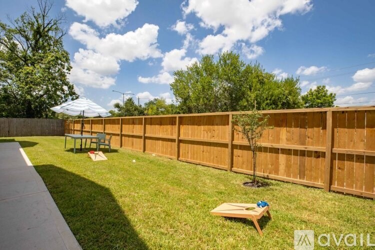 A backyard with a wooden fence and a small tree.