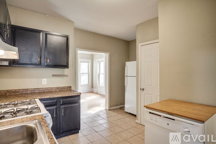 A kitchen with black cabinets and a white refrigerator.