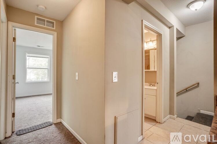 A hallway with a door on the left and a staircase on the right.