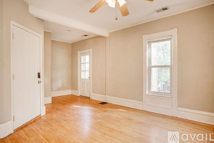 A room with a ceiling fan and two windows.