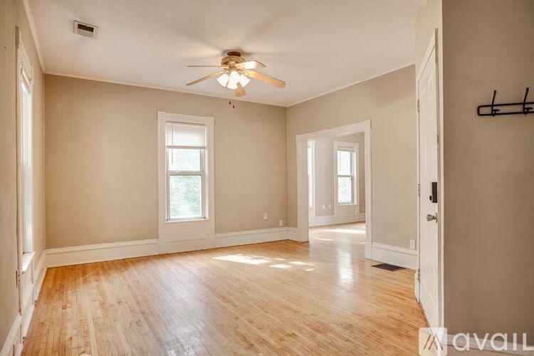 A room with a ceiling fan and wooden floors.