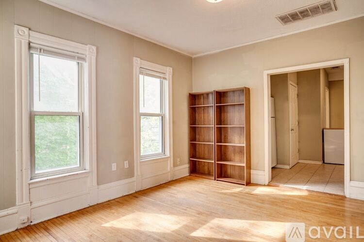 A room with a wooden floor and a large window on the left.