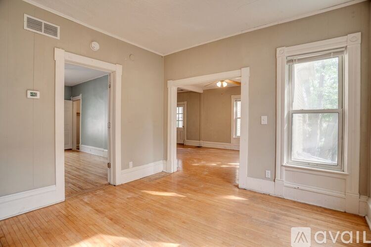 A spacious room with wooden floors and a large window.