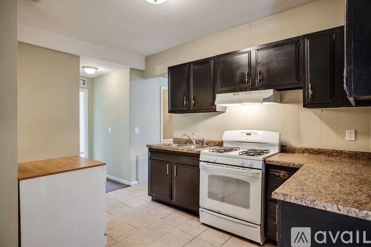A kitchen with a white stove and black cabinets.