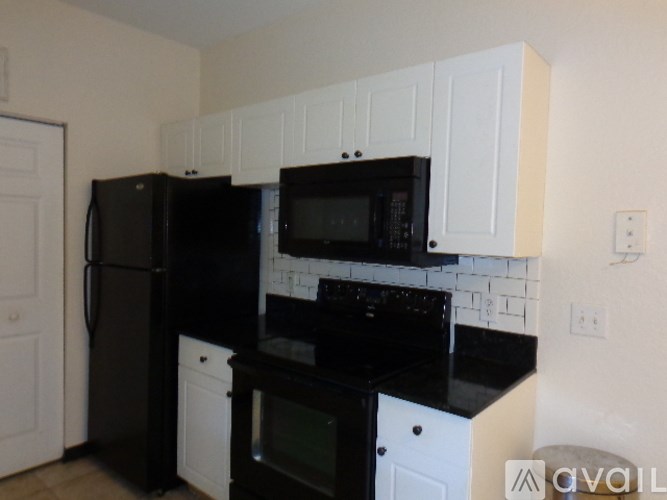 A kitchen with black appliances and white cabinets.