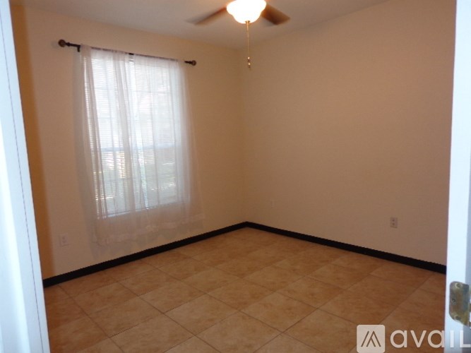 A room with a ceiling fan and a window with curtains.