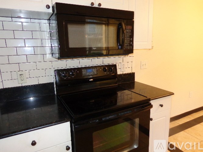 A black microwave oven is mounted above a black stove.