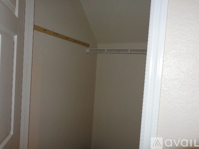 A white door is open to a small, empty room with a shelf on the wall.